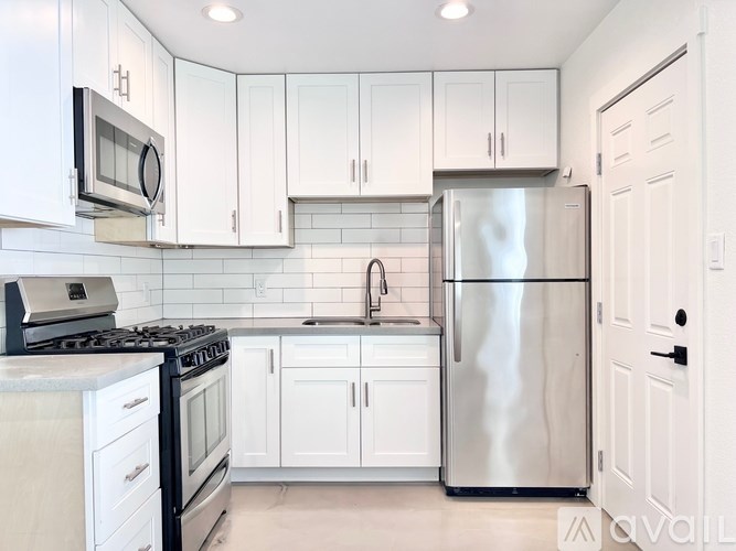 A kitchen with white cabinets and a stainless steel refrigerator.