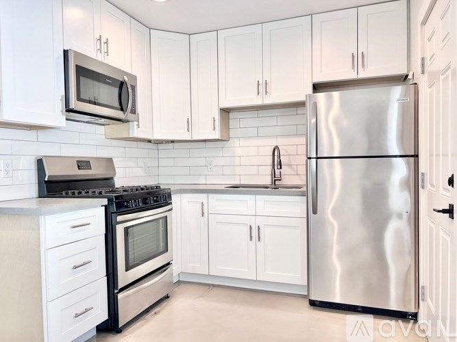 A kitchen with white cabinets and a stainless steel refrigerator.