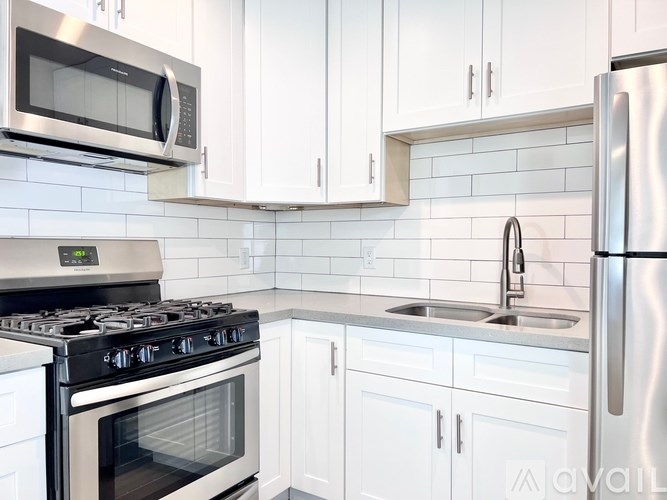 A kitchen with white cabinets and a stainless steel refrigerator.