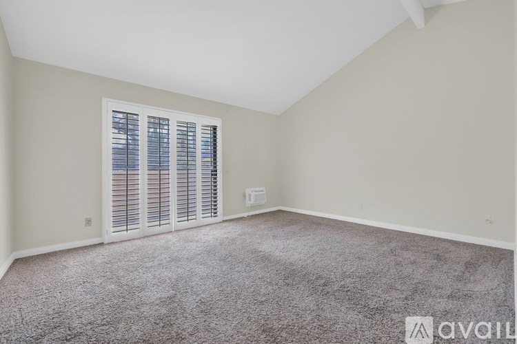 A room with a carpeted floor and a window with blinds.