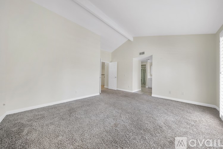 A spacious room with a carpeted floor and white walls.
