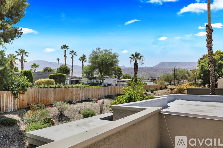 A house with a brown roof and a wooden fence with a mountain in the background.