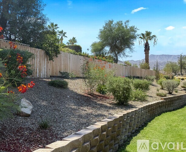 A garden with a wooden fence and red flowers.