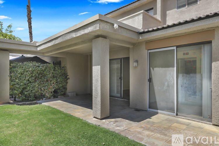 A house with a patio and a palm tree in the background.