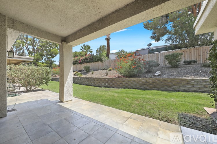 A patio with a view of a garden and a house.
