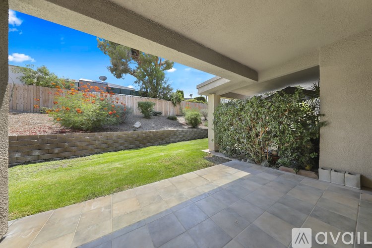 A patio with a stone floor and a wall of green plants.