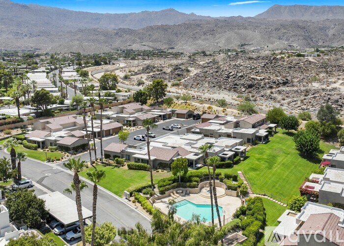 A bird's eye view of a residential area with houses, cars, and a pool.