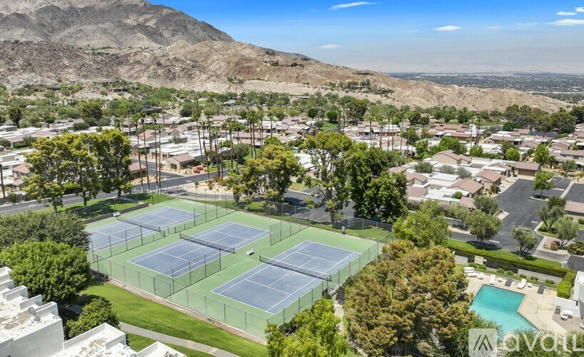 A tennis court surrounded by a fence with a mountain in the background.