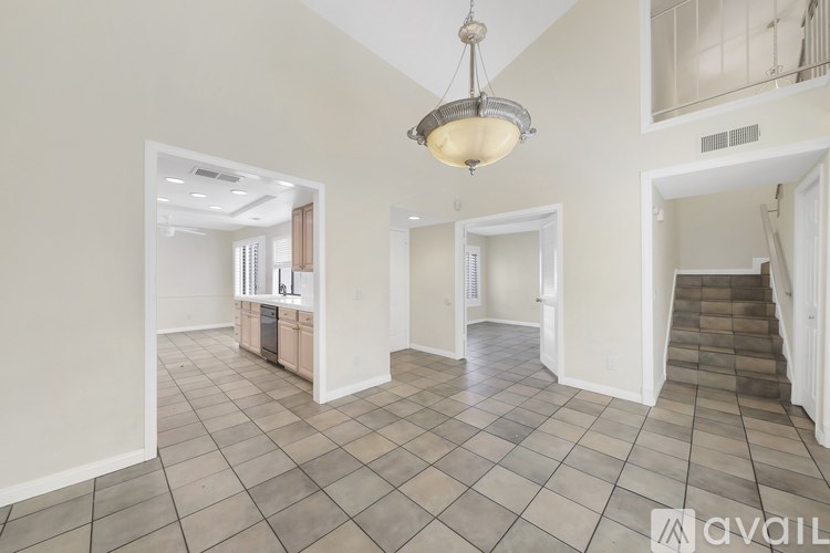 A spacious room with a tiled floor and a chandelier hanging from the ceiling.