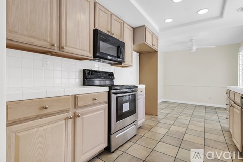 A kitchen with wooden cabinets and a black stove top oven.