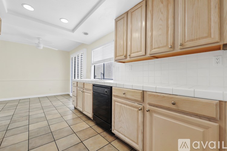 A kitchen with wooden cabinets and a black dishwasher.