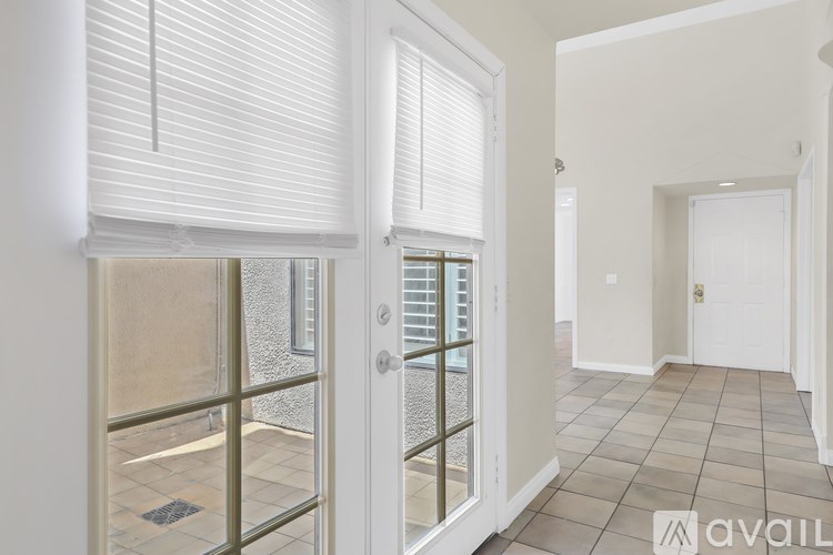 A hallway with a glass door leading to a balcony.