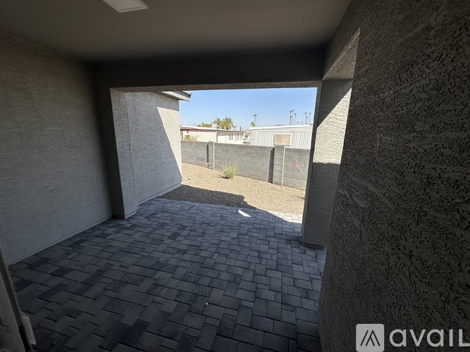 A patio area with a view of a fence and a building in the distance.