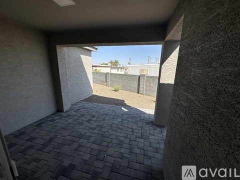 A patio area with a view of a fence and a building in the distance.