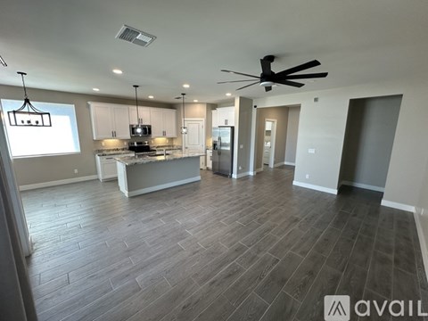 A spacious kitchen and living room with a ceiling fan and hardwood flooring.