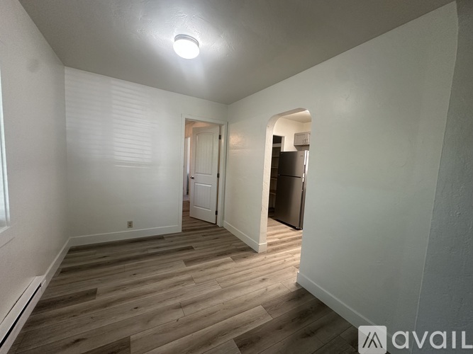 A room with wooden flooring and a doorway leading to another room.