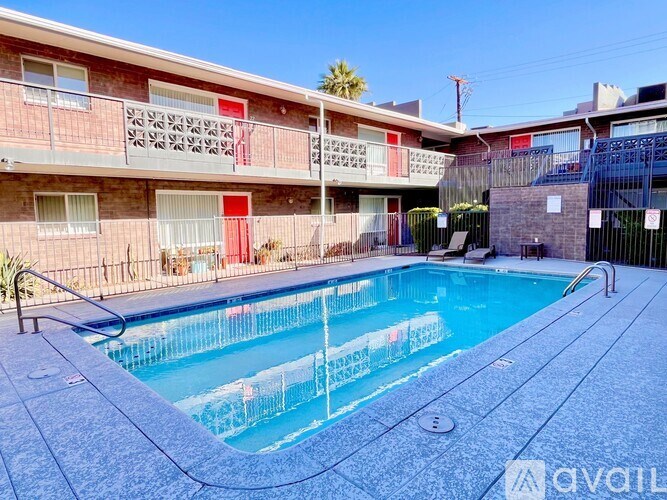 A pool in front of a red building with balconies.