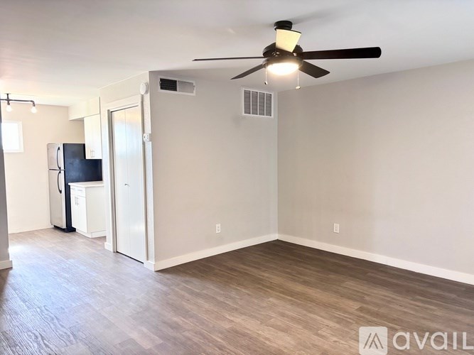 A spacious room with a ceiling fan and a refrigerator.