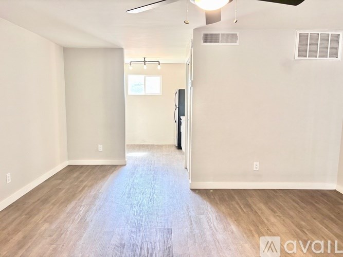 A spacious room with wood flooring and a ceiling fan.