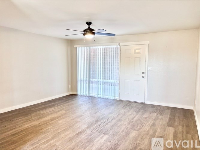 A room with a ceiling fan and a sliding door leading to a balcony.