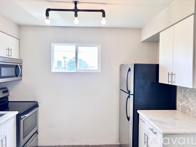 A kitchen with a black fridge and white cabinets.