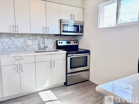 A kitchen with white cabinets and a black stove top oven.