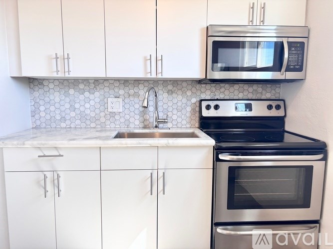 A kitchen with white cabinets and a black stove top oven.