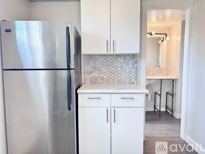 A kitchen with a stainless steel refrigerator and white cabinets.