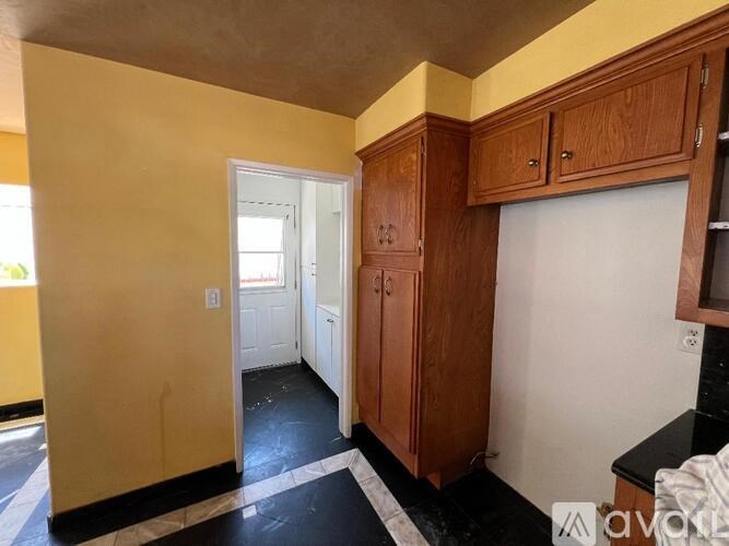 A kitchen with wooden cabinets and a black and white floor.