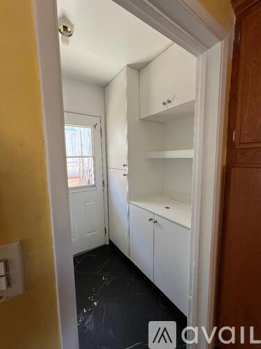 A kitchen with white cabinets and a wooden door.