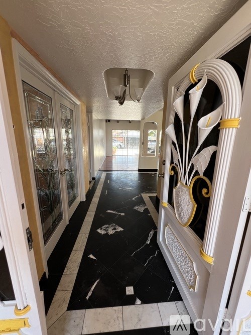 A hallway with black and white marble flooring and gold trim.
