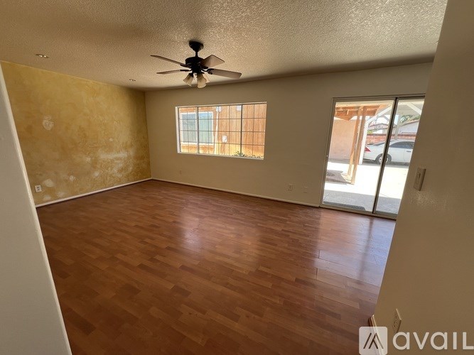 Empty room with wooden flooring and a ceiling fan.