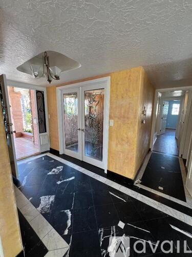 A room with a black and white floor and a fan on the ceiling.