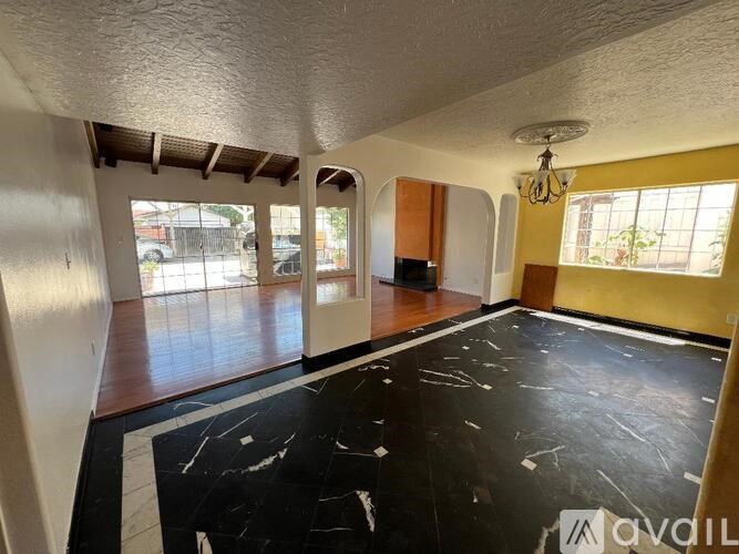A spacious room with a black marble floor and a chandelier hanging from the ceiling.