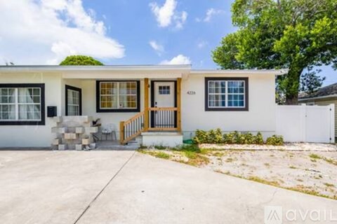 A white house with a brown door and windows is for sale.
