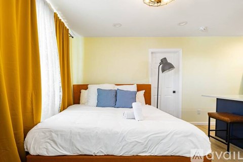 A bedroom with a white bed and yellow curtains.