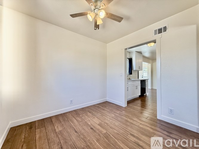 A room with a ceiling fan and wooden flooring.