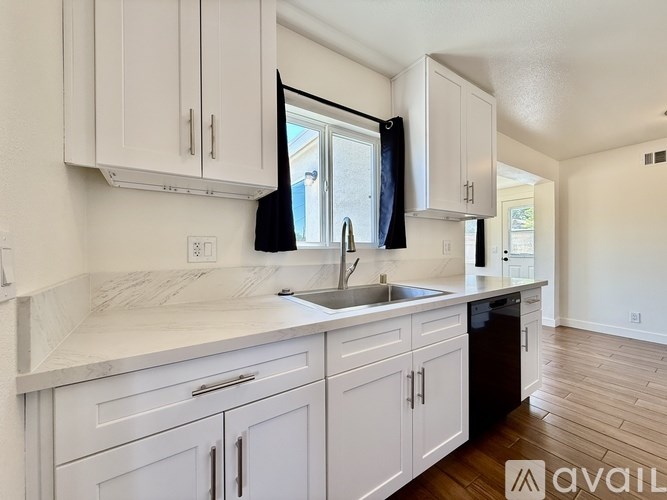 A kitchen with white cabinets and a marble countertop.