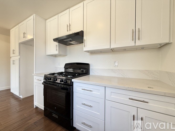 A kitchen with white cabinets and a black stove top oven.