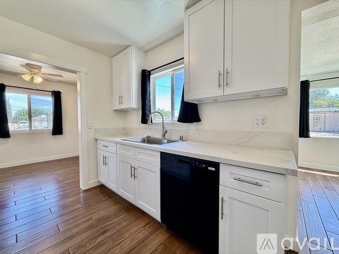 A kitchen with white cabinets and a black dishwasher.