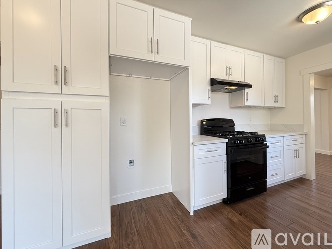 A kitchen with white cabinets and a black stove top oven.