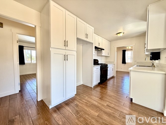 A kitchen with white cabinets and a wooden floor.