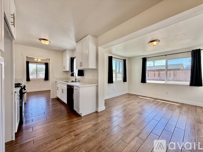 A kitchen with white cabinets and a wooden floor.