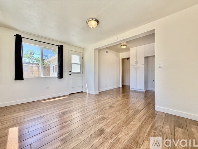 A spacious room with wooden flooring and white walls.