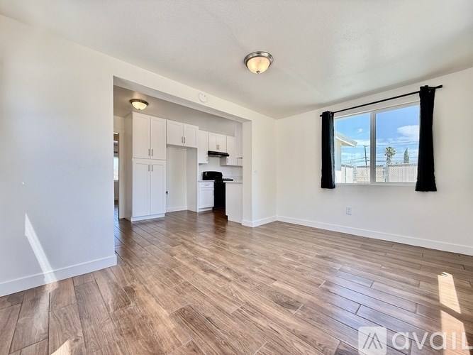 A spacious living room with wood flooring and a large window.