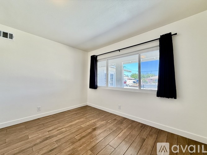 A room with a window and a wooden floor.