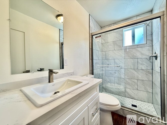 A white sink in a bathroom with a glass shower door.