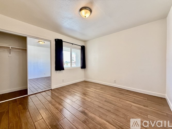 A room with wooden flooring and a window with blinds.