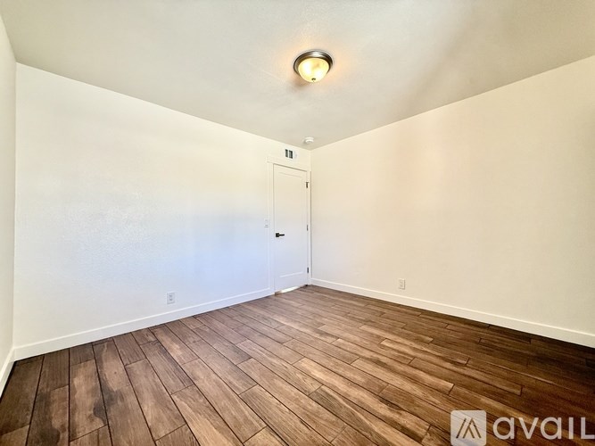 A room with wooden flooring and a white door.