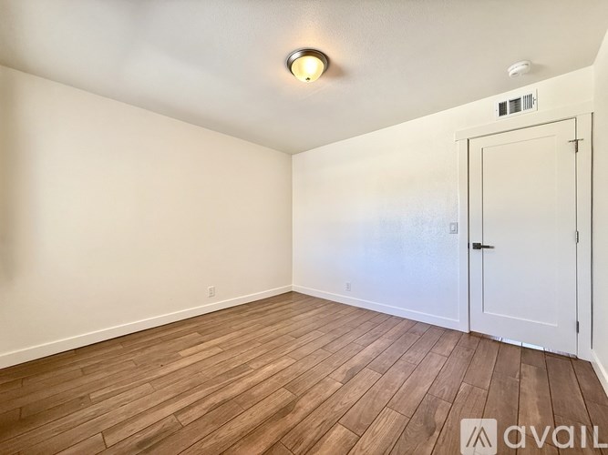 A room with wooden flooring and a white door.